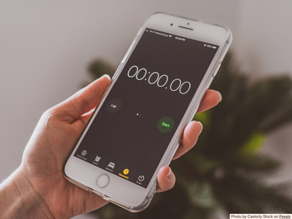 Hand setting a phone timer at an outdoor cookout table to track how long food has been out
