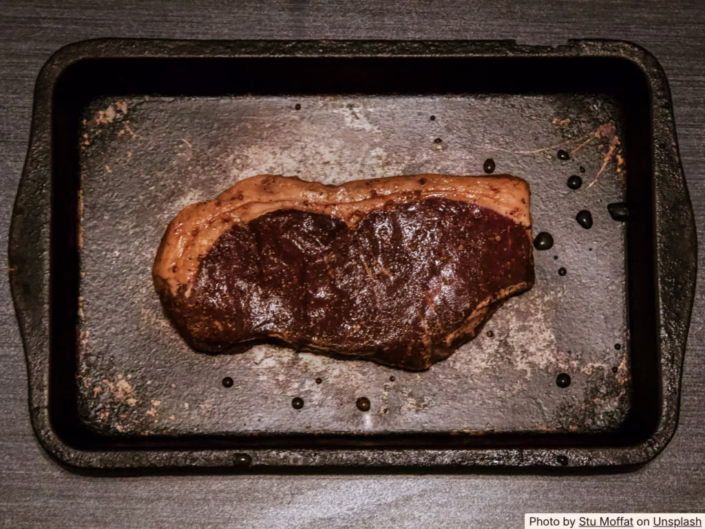 Steak being lifted from a marinade bag showing surface texture after long marinating