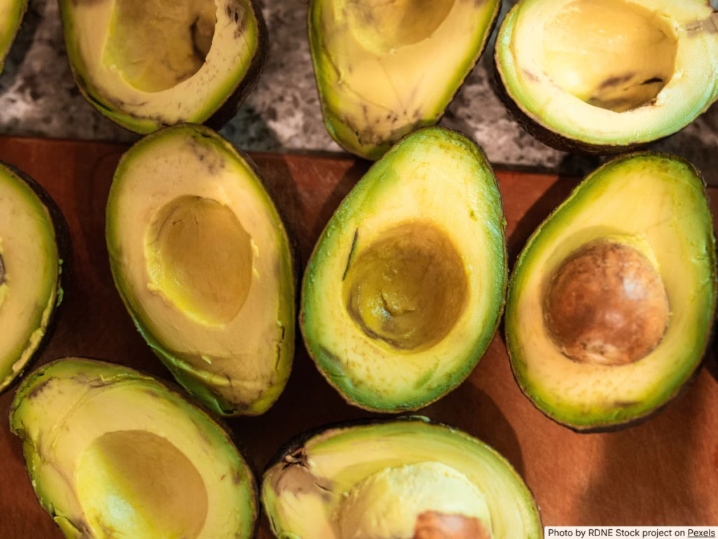 Avocado half with pit in place showing green flesh under the pit but browning around the exposed edges