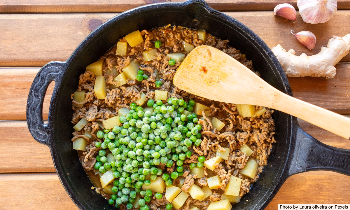 Cast iron skillet hash with browned potatoes, onion, and ground beef on a sunny kitchen counter