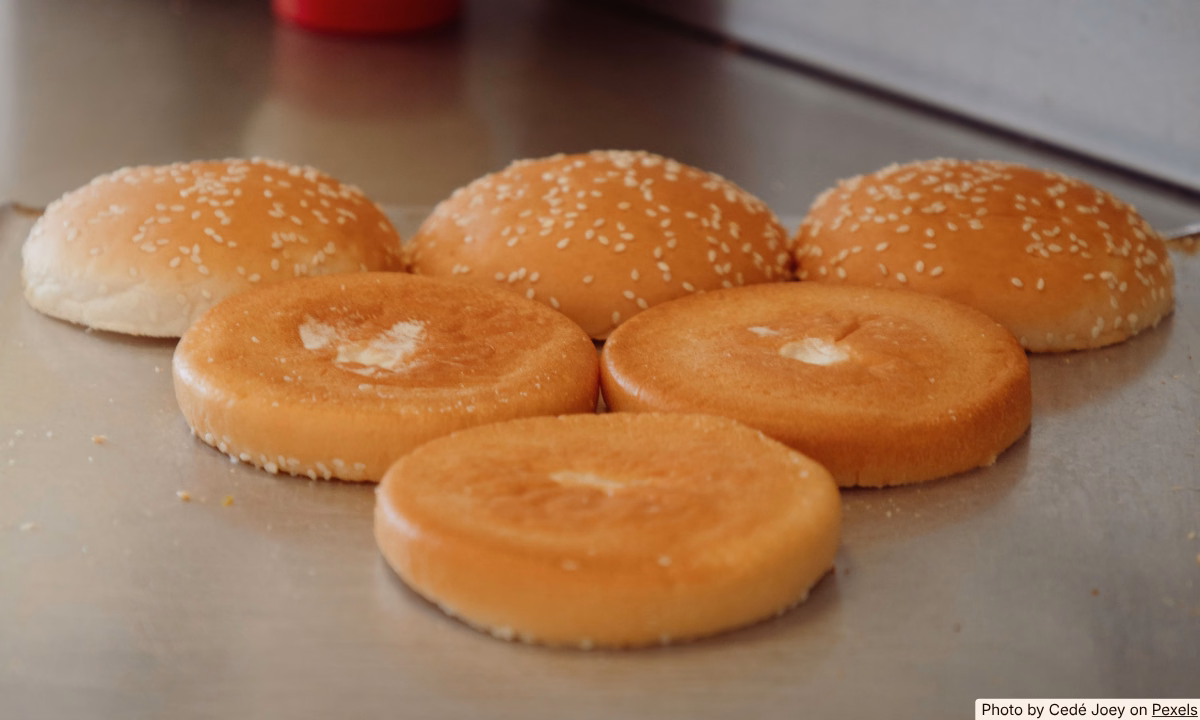 Five leftover hamburger buns in an open bag on a kitchen counter