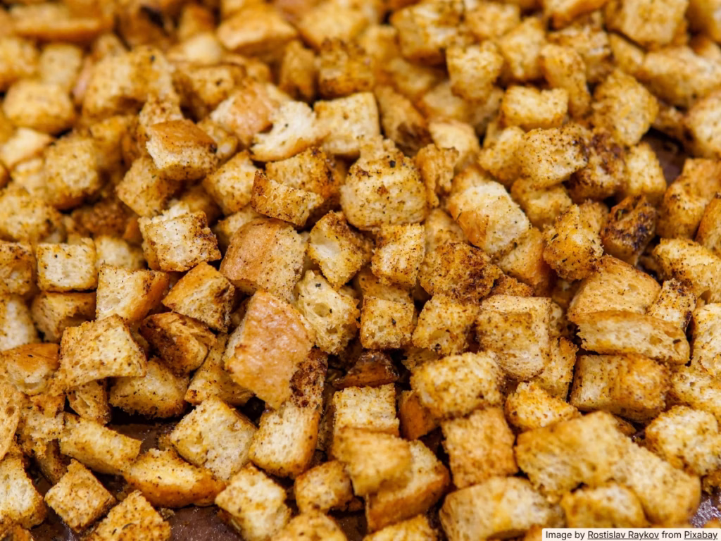 Homemade golden croutons on a baking sheet, made from cubed day-old bread