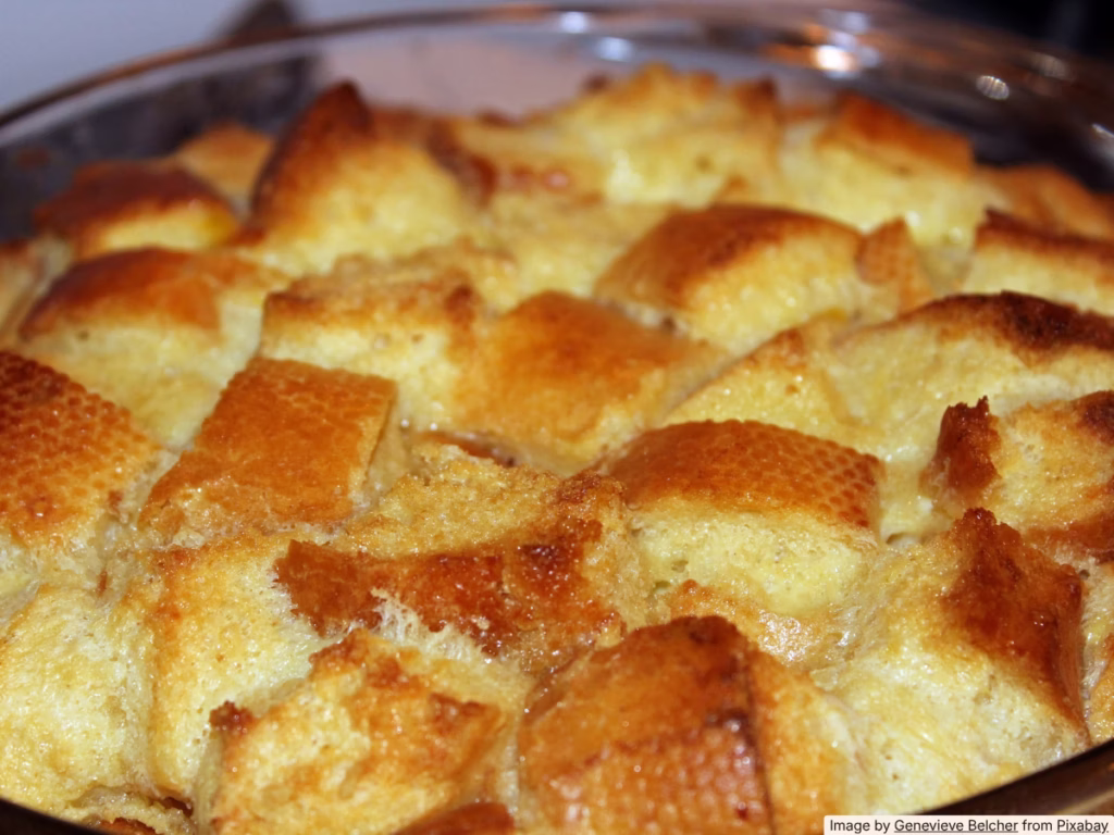 Warm bread pudding in a ceramic baking dish made from cubed hamburger buns and custard
