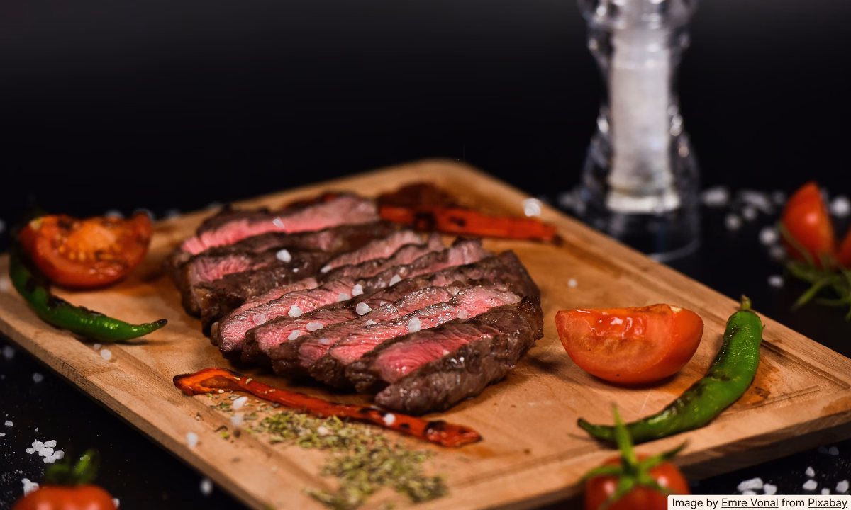 Thinly sliced leftover steak on a wooden cutting board, ready to use as a pre-cooked ingredient