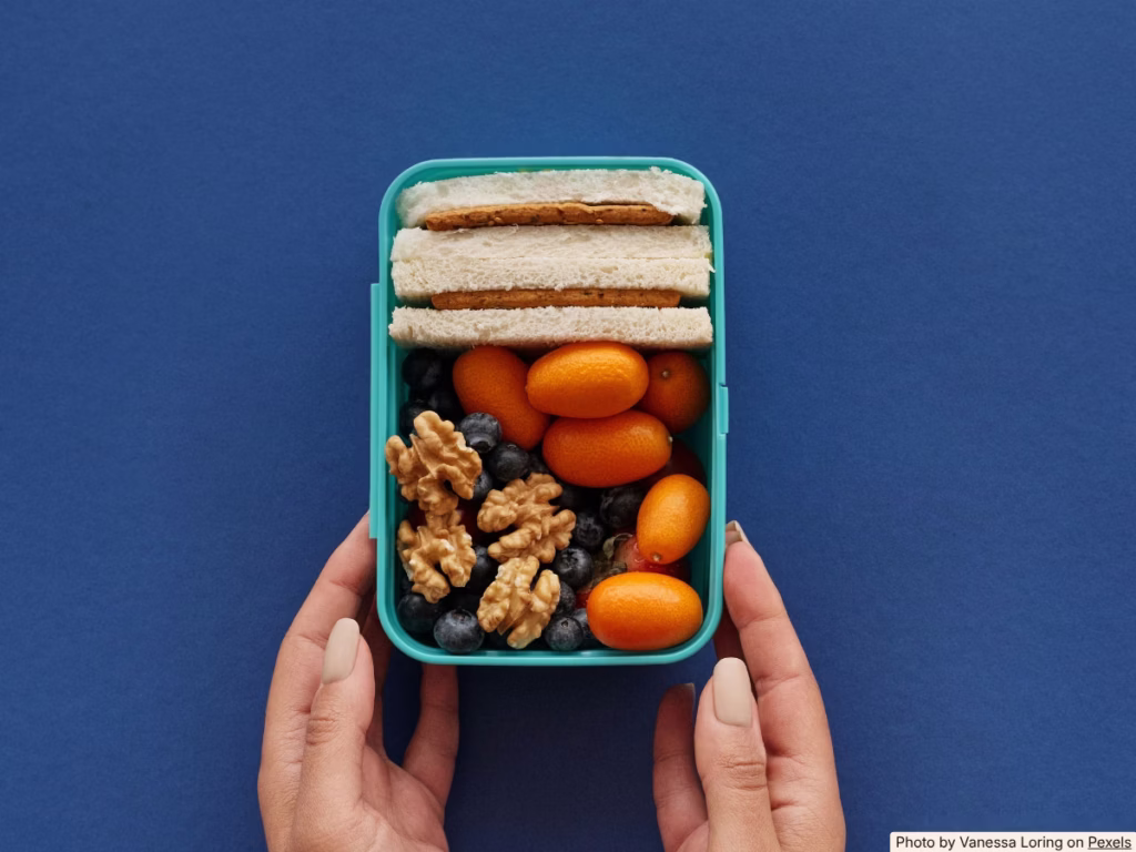 Hands packing a school lunchbox on a bright kitchen counter on a busy morning