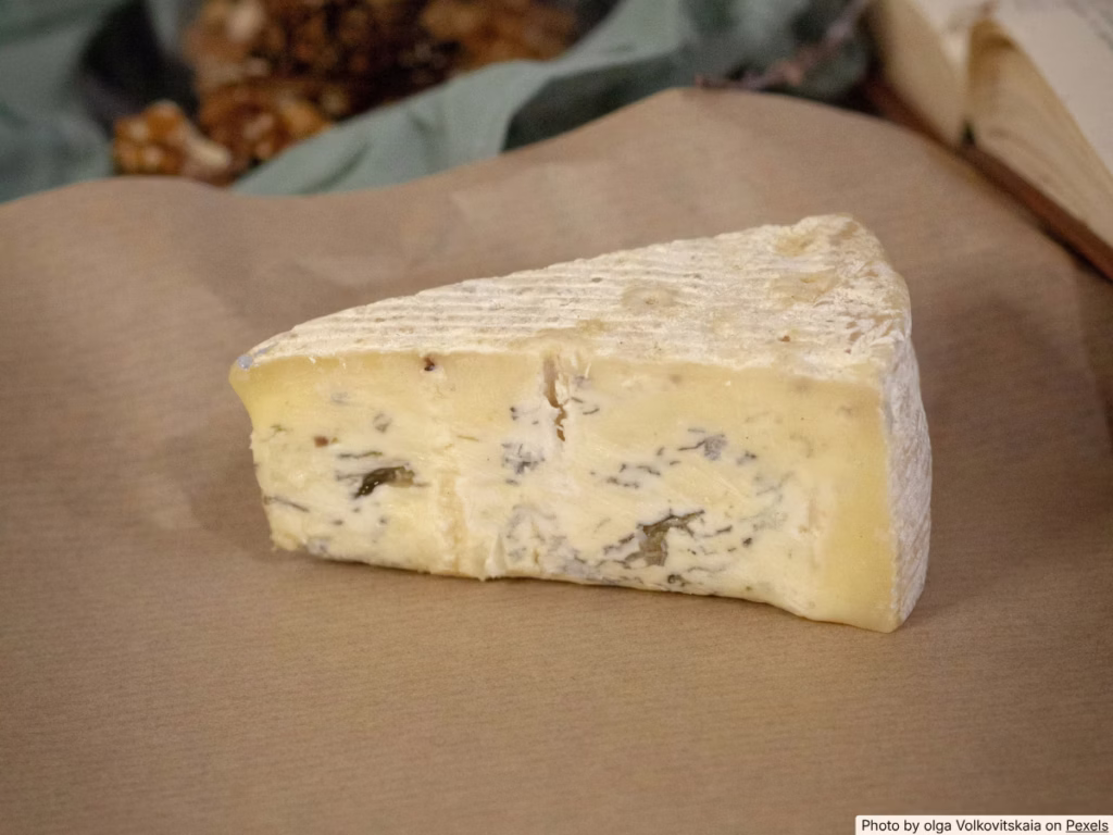Block of cheese wrapped in parchment paper on a kitchen counter, natural light