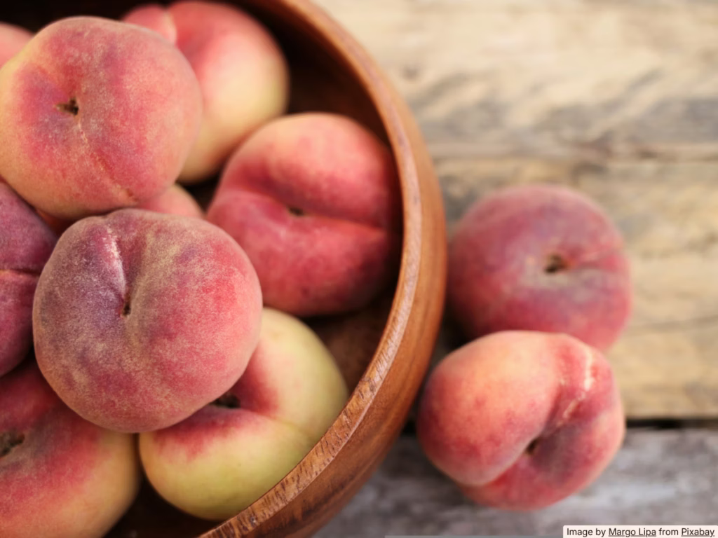 Fresh peaches in a ceramic bowl on a sunny kitchen counter, warm natural light