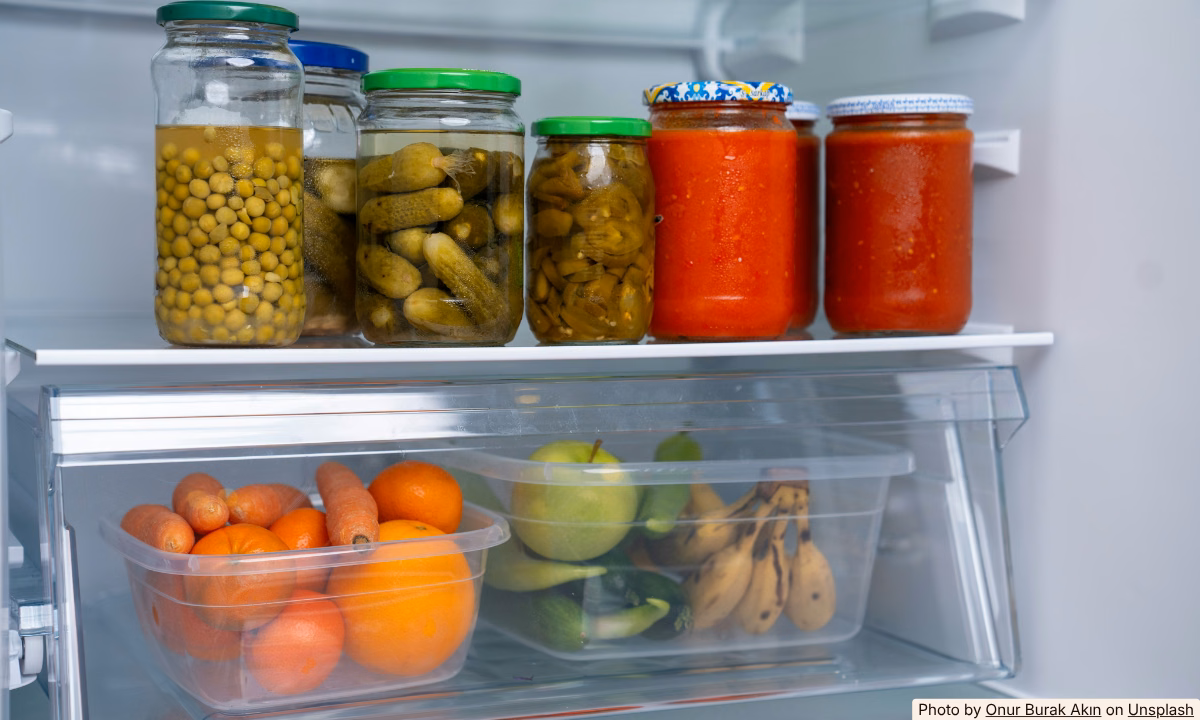 Open home refrigerator packed with leftover party food in containers and foil-covered dishes
