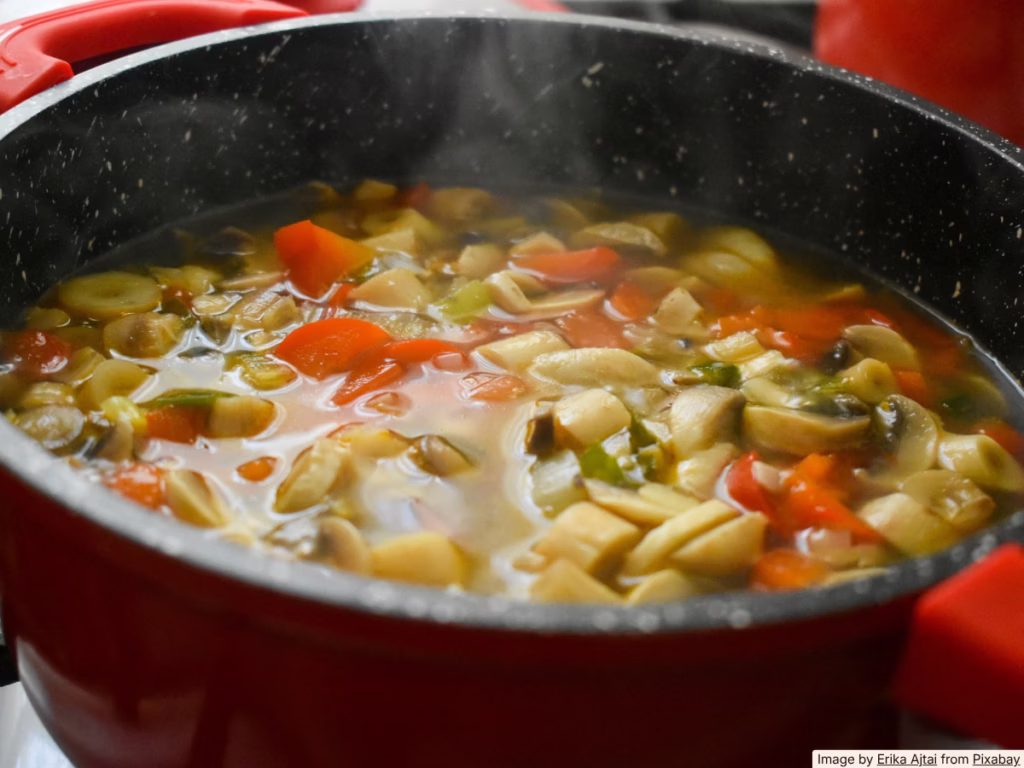 Colorful vegetable soup simmering in a pot on a bright home kitchen stovetop