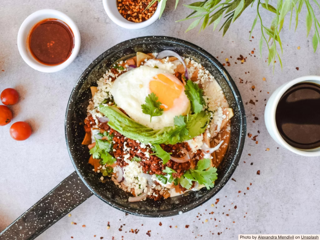 Chilaquiles with fried eggs, cotija cheese and red salsa in a skillet, made from leftover tortilla chips