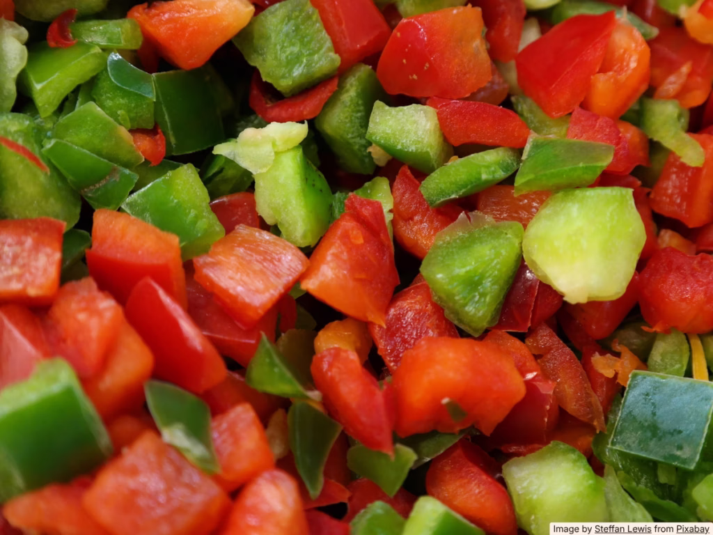 Sliced bell peppers stored in a clear airtight container with a paper towel on the bottom